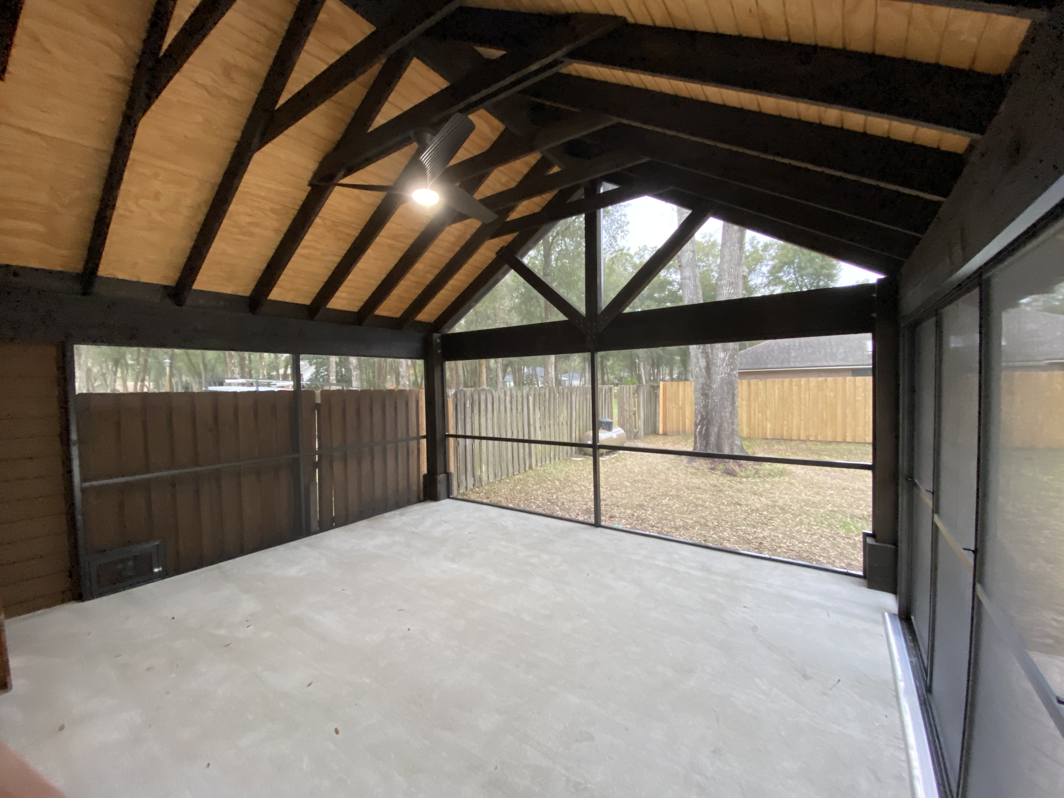 This beautiful screened-in lanai has a very high roof with exposed beams, electrical, and a ceiling fan with light. Screen Enclosures and More takes pride in the custom projects we build and design for our clients.