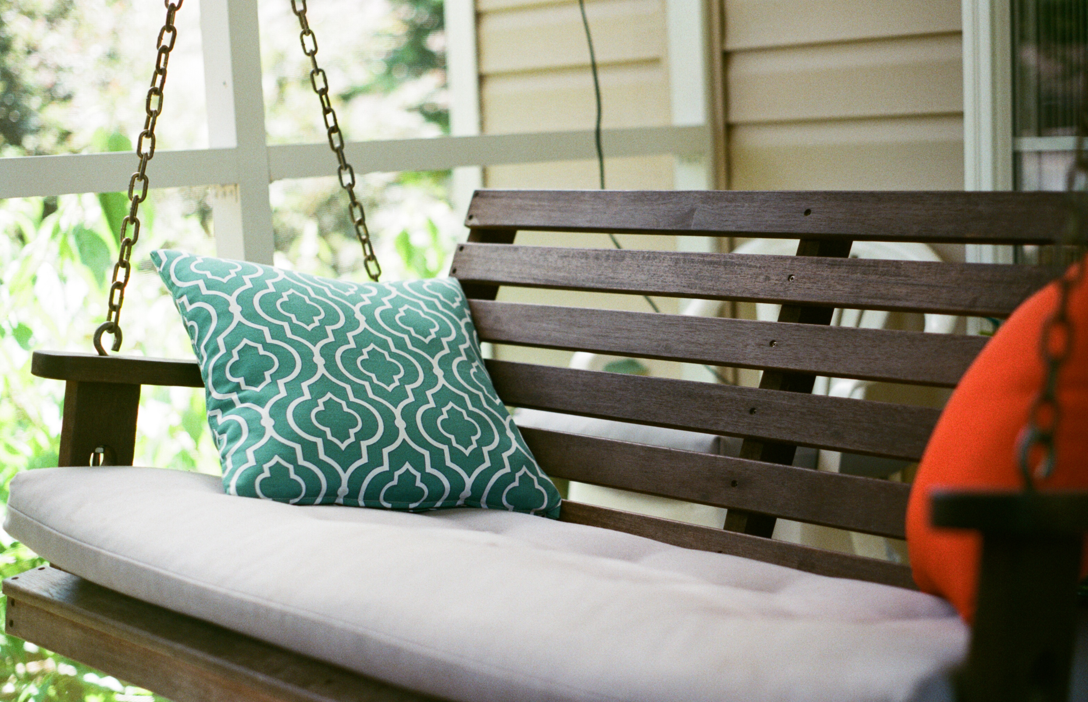 A classic porch swing hangs from the ceiling with a few colorful cushions.