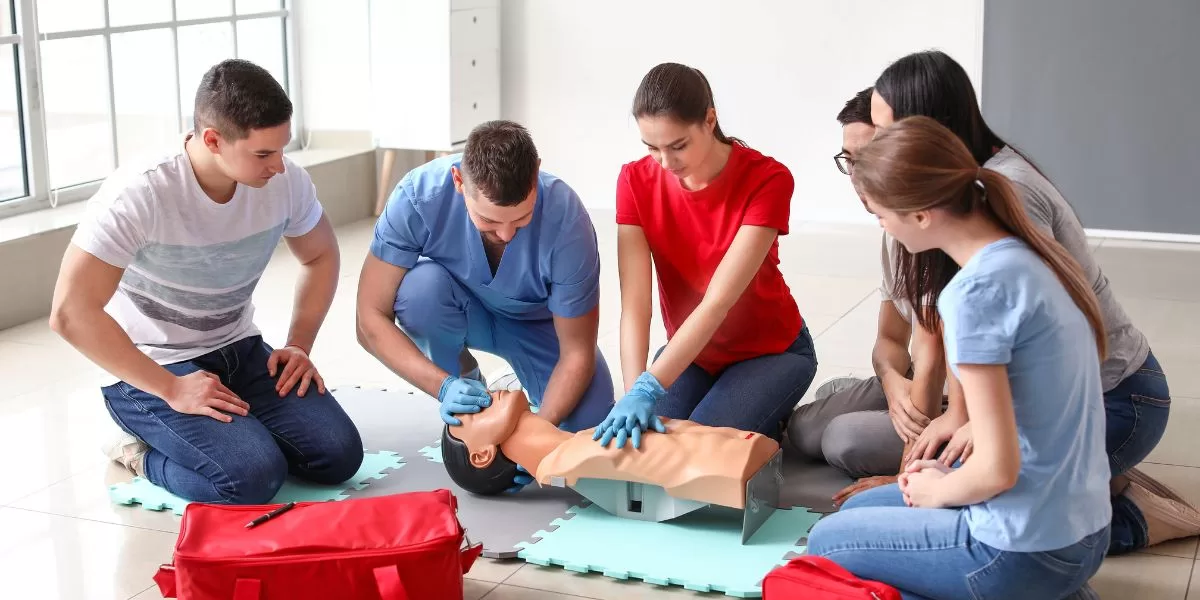 a group of people is learning CPR by practicing their skills on a CPR dummy.