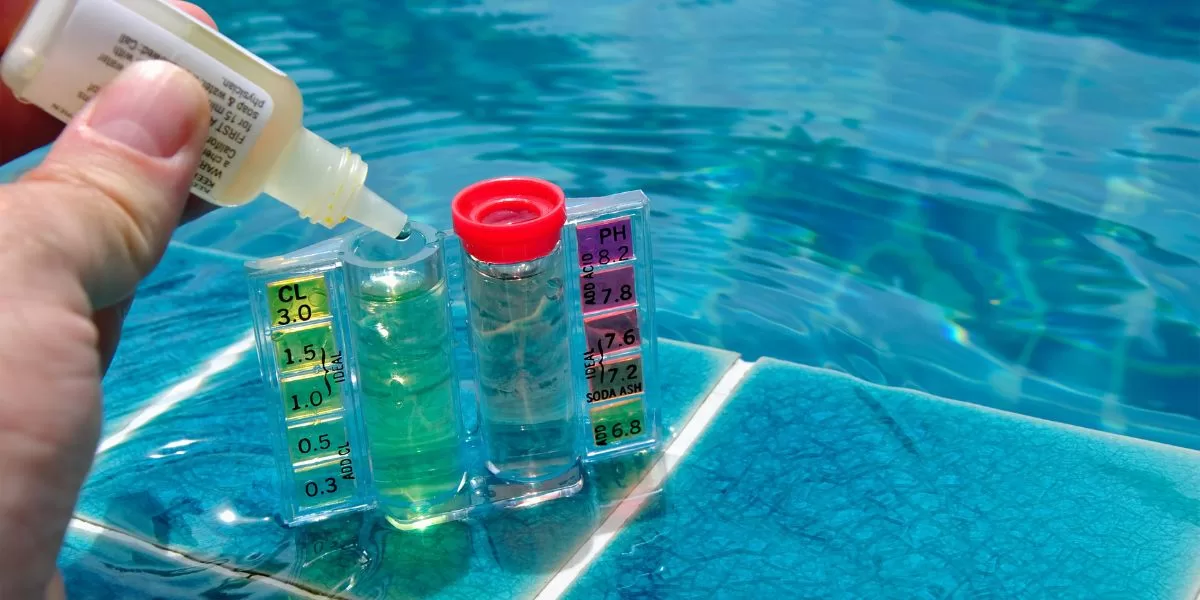 A person is testing their pool chemicals to make sure the pool is balanced and maintained.
