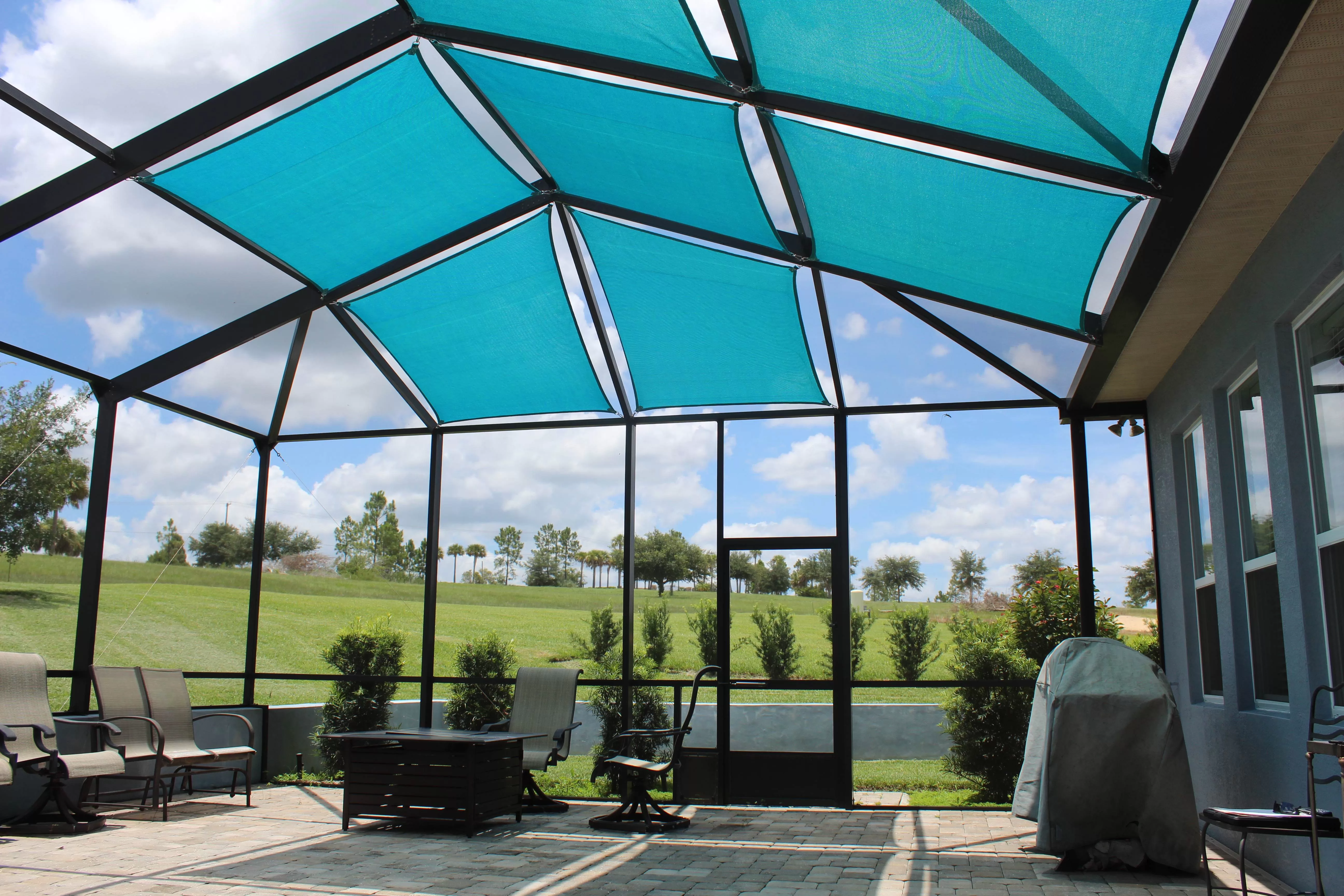 A screened-in patio has shade sails on top to prevent the harsh sun and heat from entering their enclosed patio space. 